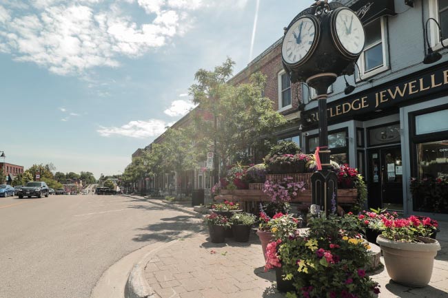 Downtown Uxbridge in the summer with flower planters and an old clock post.